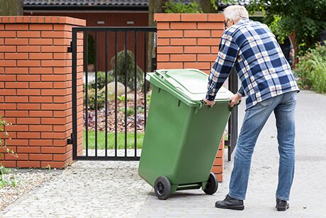 Resident taking trash bin back into his yard.